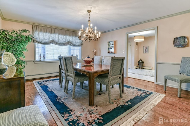 dining area with crown molding, hardwood / wood-style flooring, and a baseboard heating unit