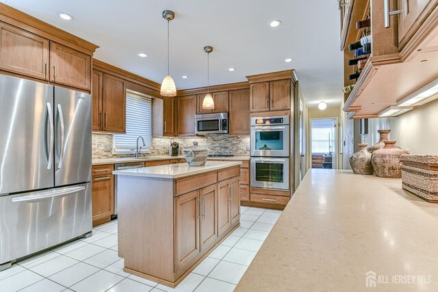 kitchen featuring stainless steel appliances, a center island, pendant lighting, and light tile patterned floors