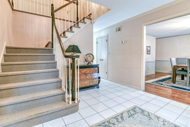 stairs featuring tile patterned floors and crown molding