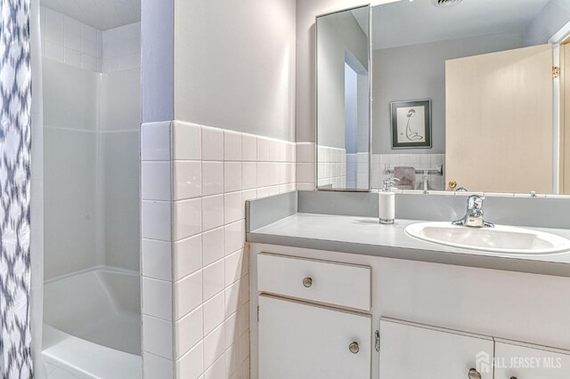 bathroom with tile walls, vanity, and shower / bath combo