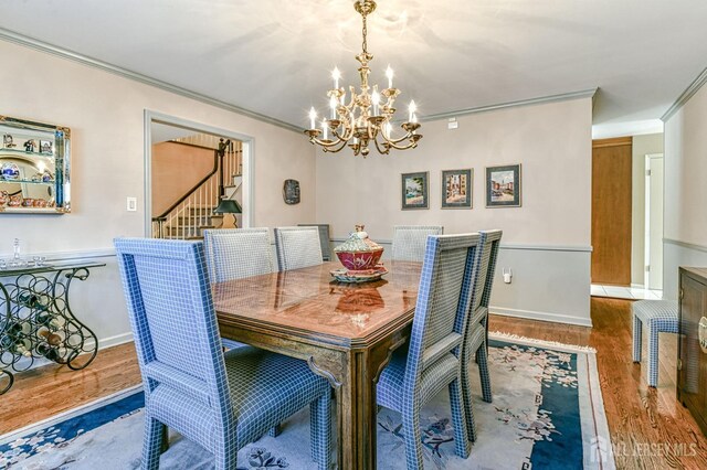 dining space with an inviting chandelier, crown molding, and hardwood / wood-style floors