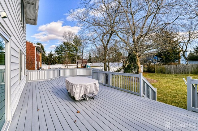 wooden deck featuring a playground and a lawn