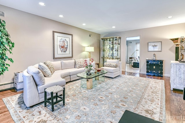 living room with a baseboard heating unit and hardwood / wood-style flooring