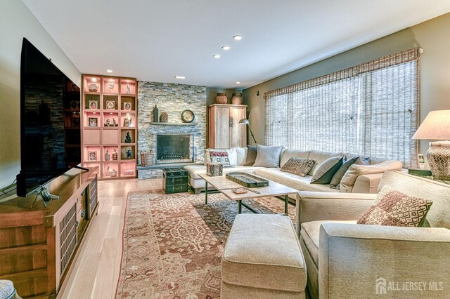 living room with light wood-type flooring, built in shelves, and a fireplace