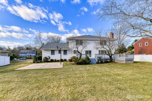 rear view of house featuring a patio area, a wooden deck, and a yard