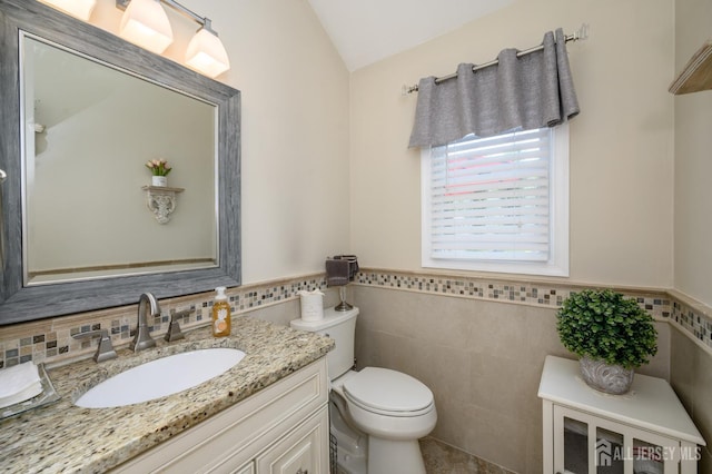 1 Wilfred Rd, Manalapan, NJ 07726 - half bathroom featuring vanity, tile walls, vaulted ceiling, and wainscoting