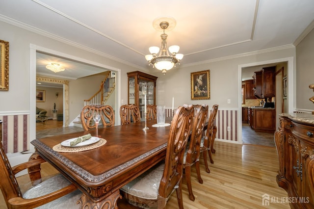 1 Wilfred Rd, Manalapan, NJ 07726 - dining room featuring a chandelier, light wood-style floors, a wainscoted wall, crown molding, and stairs