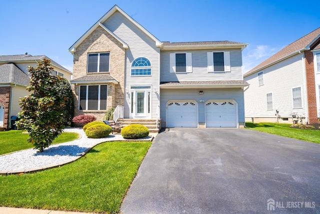 traditional-style house with an attached garage, driveway, and a front yard