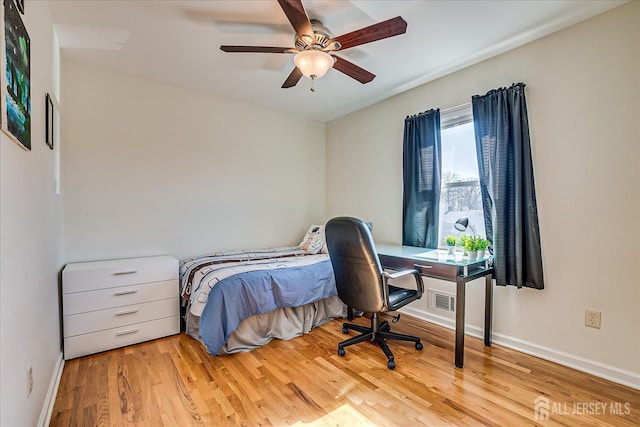 bedroom featuring visible vents, a ceiling fan, baseboards, and wood finished floors