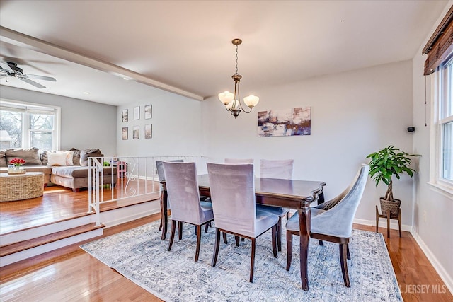 dining space with ceiling fan with notable chandelier, wood finished floors, and baseboards