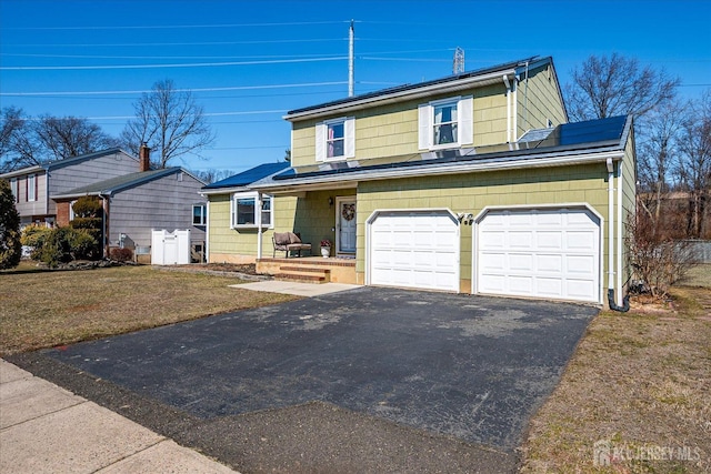 traditional-style home featuring solar panels, aphalt driveway, a garage, and a front lawn