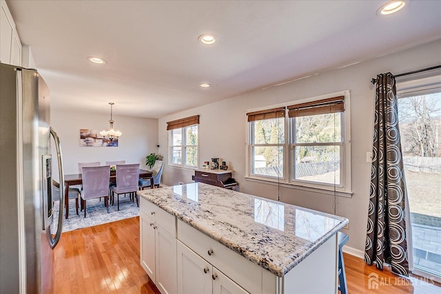 kitchen featuring white cabinetry, hanging light fixtures, stainless steel refrigerator with ice dispenser, and light wood-type flooring