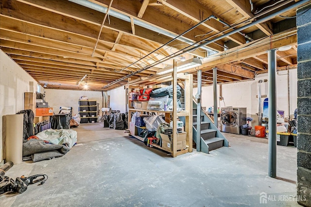 unfinished basement featuring washing machine and clothes dryer and stairs