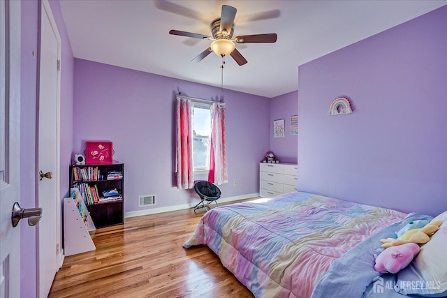 bedroom featuring light wood finished floors, visible vents, a ceiling fan, and baseboards