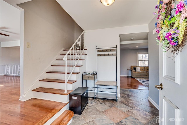 stairs with stone finish floor, baseboards, and ceiling fan