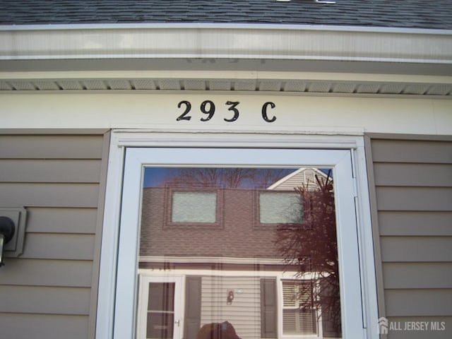 doorway to property with roof with shingles