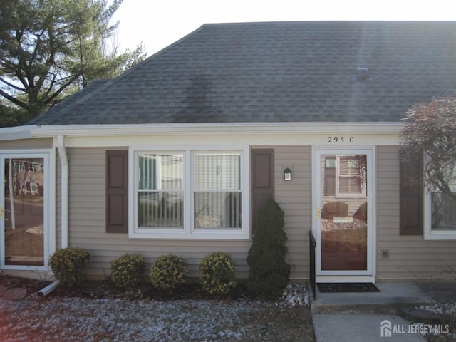 doorway to property with roof with shingles