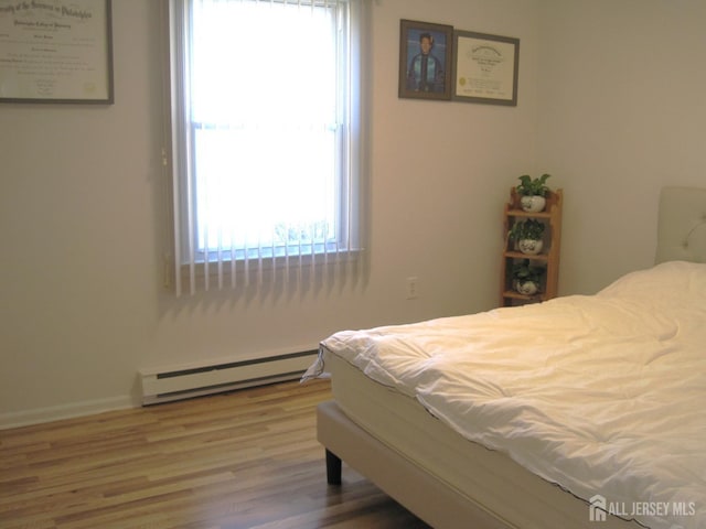 bedroom featuring baseboard heating and wood finished floors