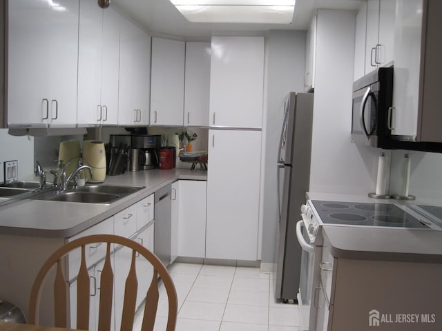 kitchen with light tile patterned floors, stainless steel appliances, a sink, and white cabinetry