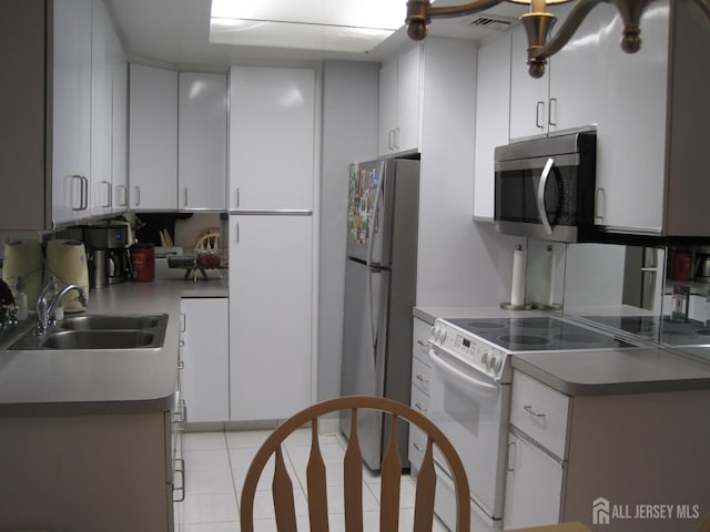 kitchen with electric stove, stainless steel microwave, visible vents, freestanding refrigerator, and a sink