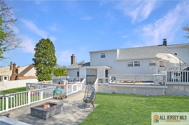 rear view of house featuring a fire pit, a deck, a patio area, and roof with shingles