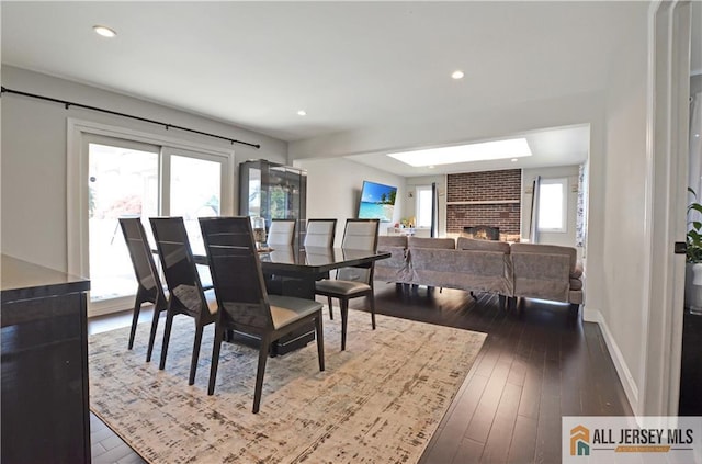 dining space featuring a fireplace, dark wood-style flooring, recessed lighting, and baseboards