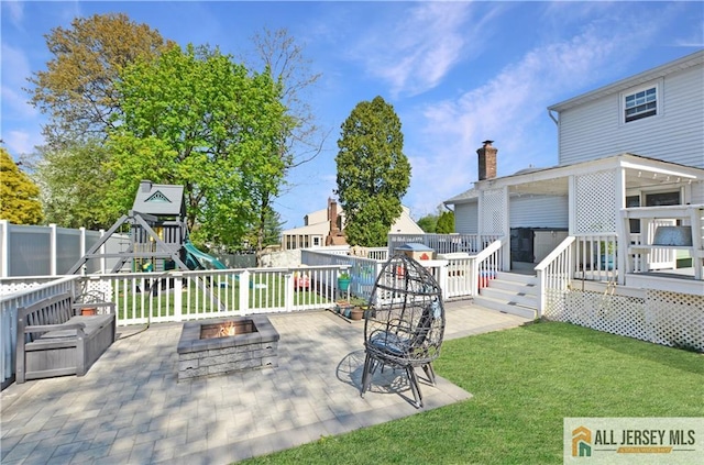 view of patio / terrace with an outdoor fire pit, a playground, and a deck