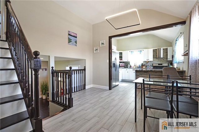 dining space featuring vaulted ceiling, wood finished floors, and baseboards