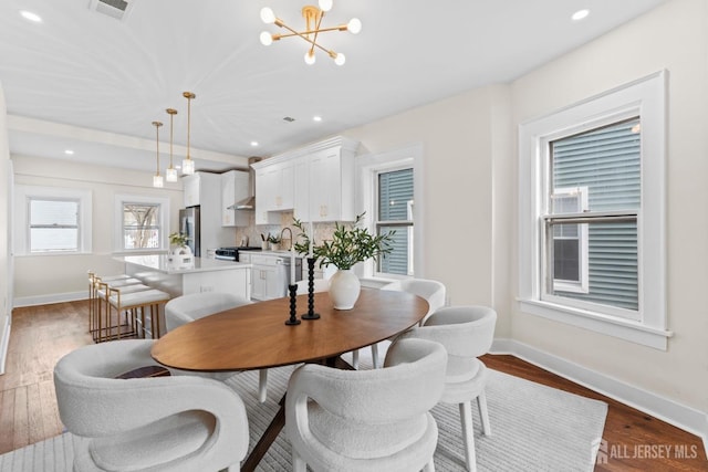 dining area with dark wood-style floors, a notable chandelier, baseboards, and visible vents