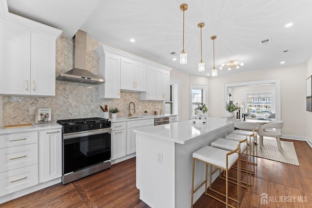 kitchen with wall chimney range hood, gas stove, visible vents, and dark wood-style flooring