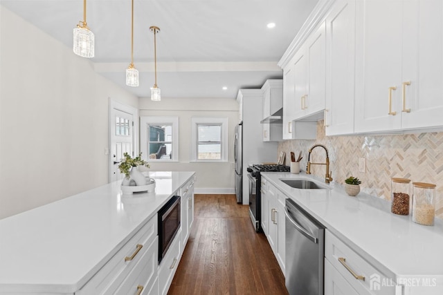 kitchen featuring under cabinet range hood, light countertops, decorative backsplash, appliances with stainless steel finishes, and a sink