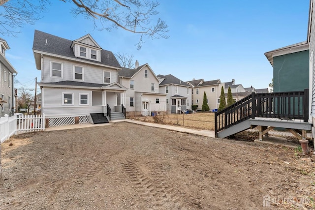 rear view of property with a residential view, roof with shingles, and fence