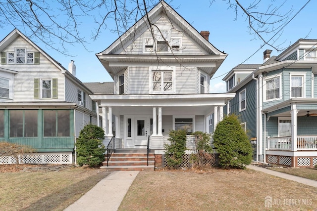 view of front of home featuring a porch, a chimney, and a sunroom