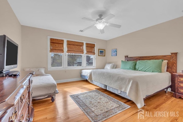 bedroom featuring ceiling fan, light wood-style flooring, baseboards, and visible vents