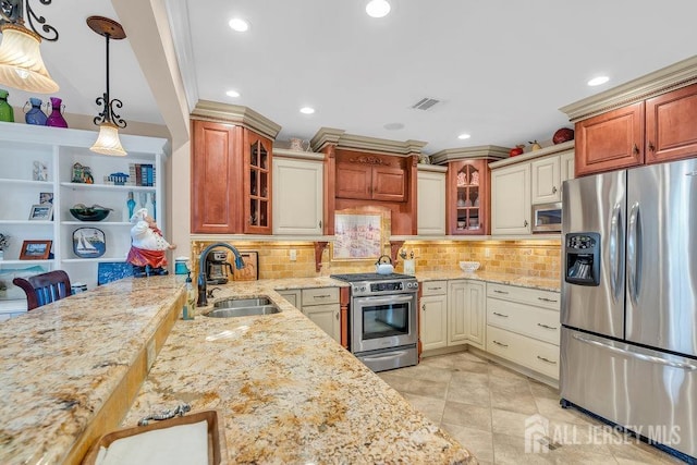 kitchen with a sink, light stone counters, visible vents, glass insert cabinets, and appliances with stainless steel finishes