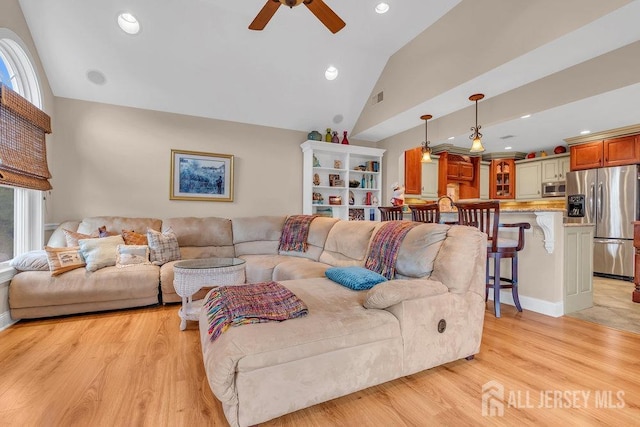living area featuring a healthy amount of sunlight, light wood finished floors, a ceiling fan, and visible vents
