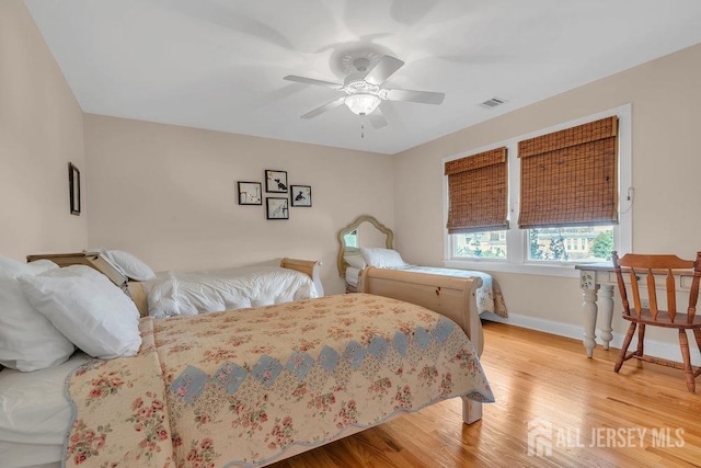 bedroom featuring light wood-type flooring, baseboards, visible vents, and a ceiling fan