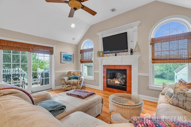 living room with ceiling fan, lofted ceiling, a glass covered fireplace, and wood finished floors