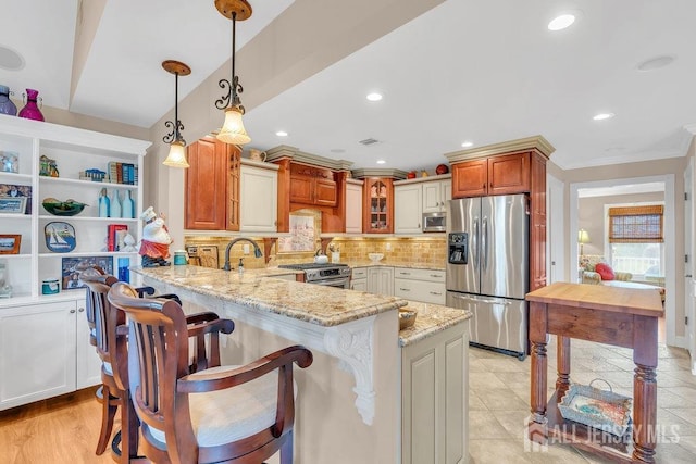 kitchen featuring a peninsula, glass insert cabinets, stainless steel appliances, decorative backsplash, and light stone counters