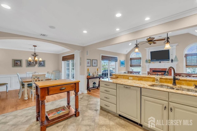 kitchen featuring ornamental molding, visible vents, a sink, a wainscoted wall, and arched walkways