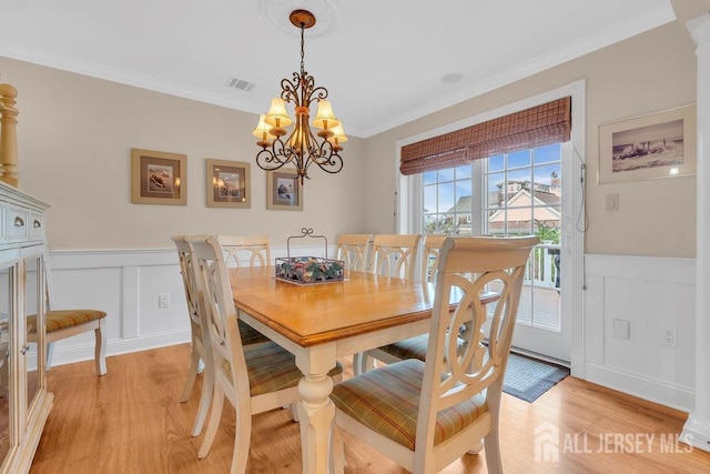 dining room featuring crown molding, an inviting chandelier, wainscoting, and visible vents