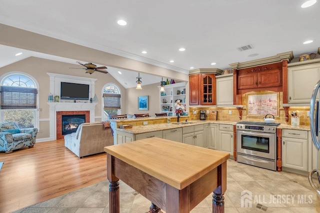 kitchen featuring a sink, a peninsula, visible vents, a ceiling fan, and appliances with stainless steel finishes