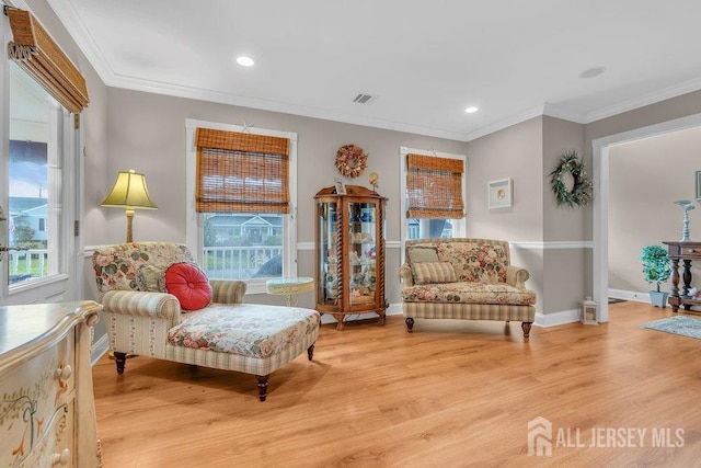 sitting room featuring light wood-style flooring, crown molding, and plenty of natural light