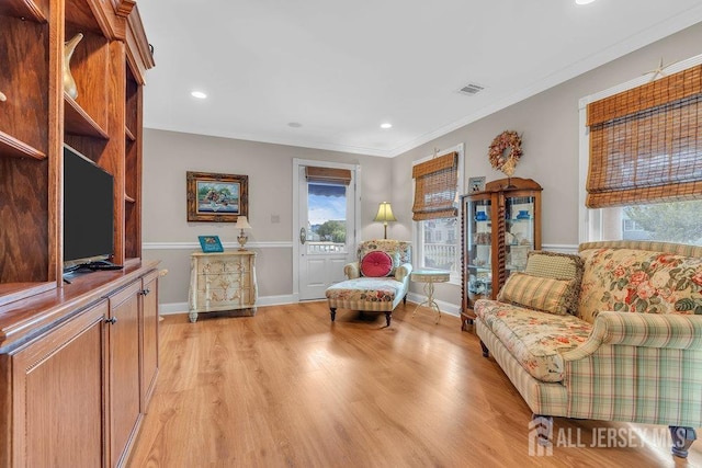 living area with ornamental molding, light wood-style flooring, visible vents, and recessed lighting