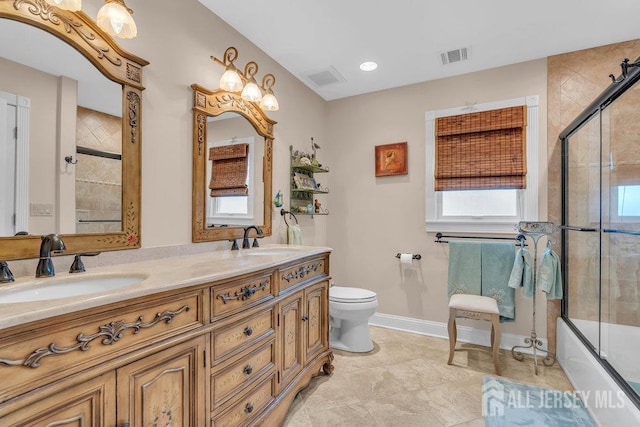 bathroom featuring baseboards, toilet, a sink, and double vanity