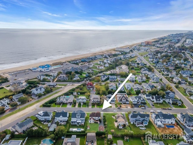 drone / aerial view featuring a water view, a beach view, and a residential view