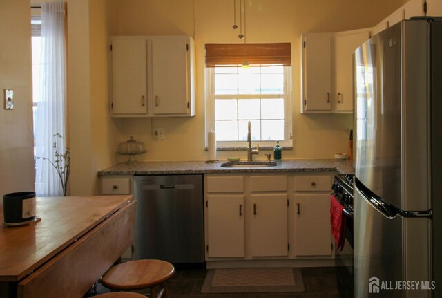 kitchen featuring stainless steel appliances, light countertops, a sink, and white cabinetry