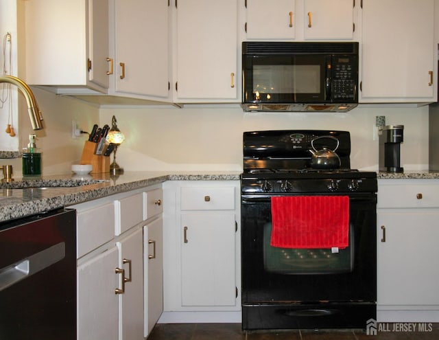 kitchen with black appliances, light stone counters, white cabinets, and a sink