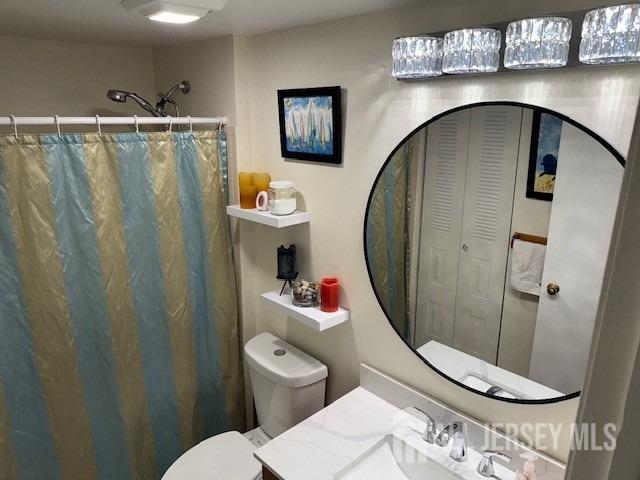 full bathroom featuring a shower with shower curtain, vanity, and toilet