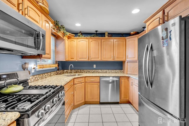 kitchen featuring light tile patterned floors, light stone countertops, stainless steel appliances, a sink, and recessed lighting